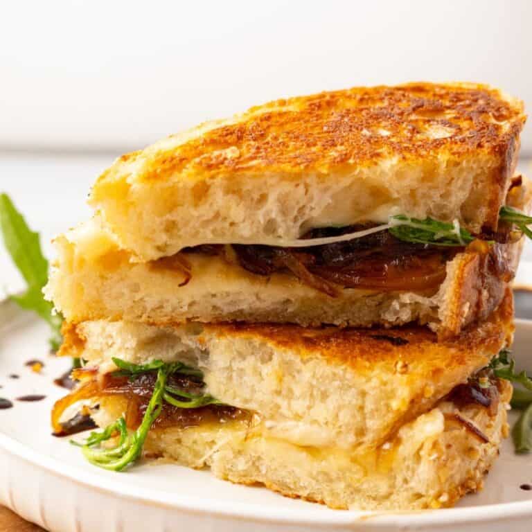 Sliced French onion grilled cheese stacked on a plate.