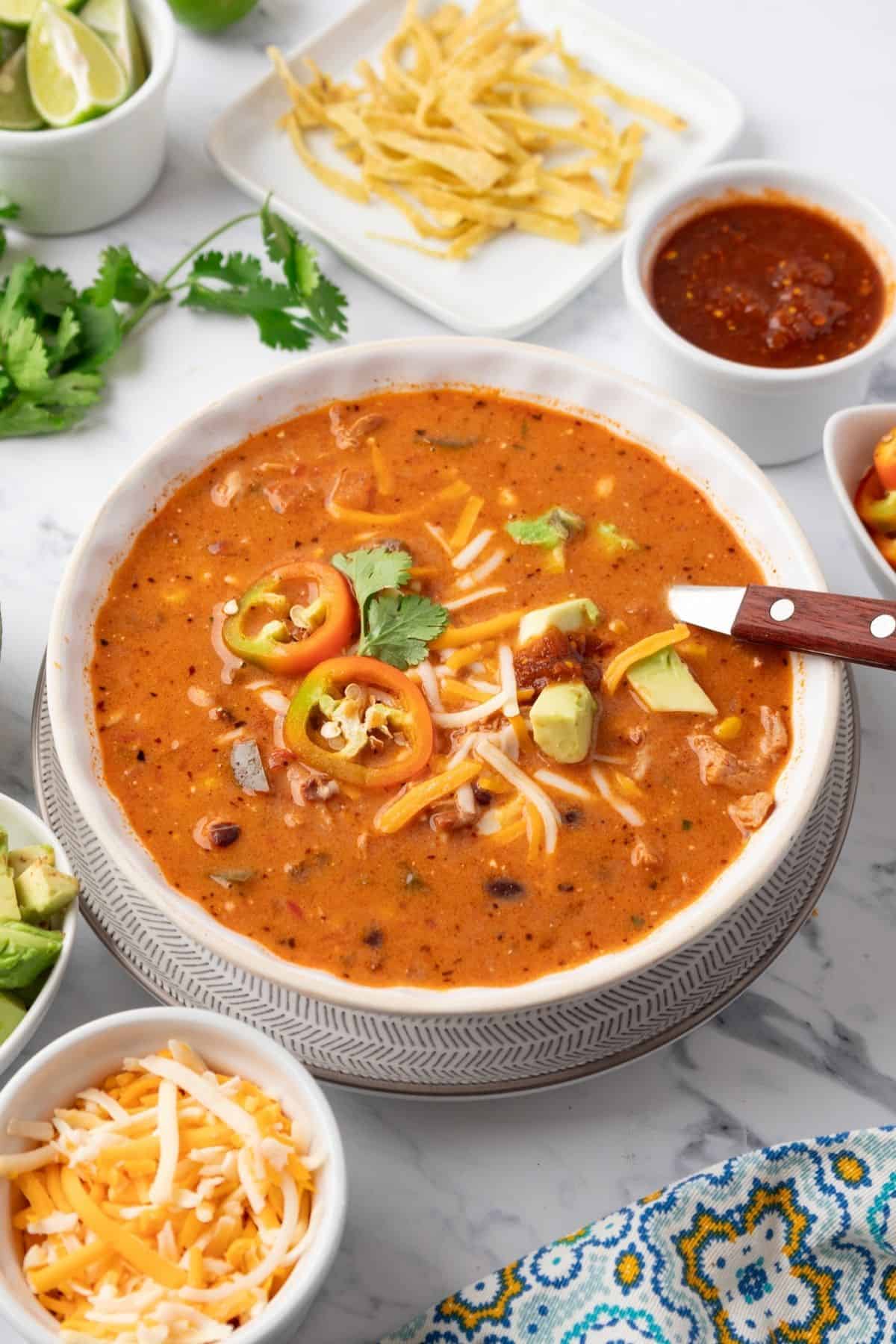 A bowl of creamy chicken taco soup with a spoon resting in the bowl. 