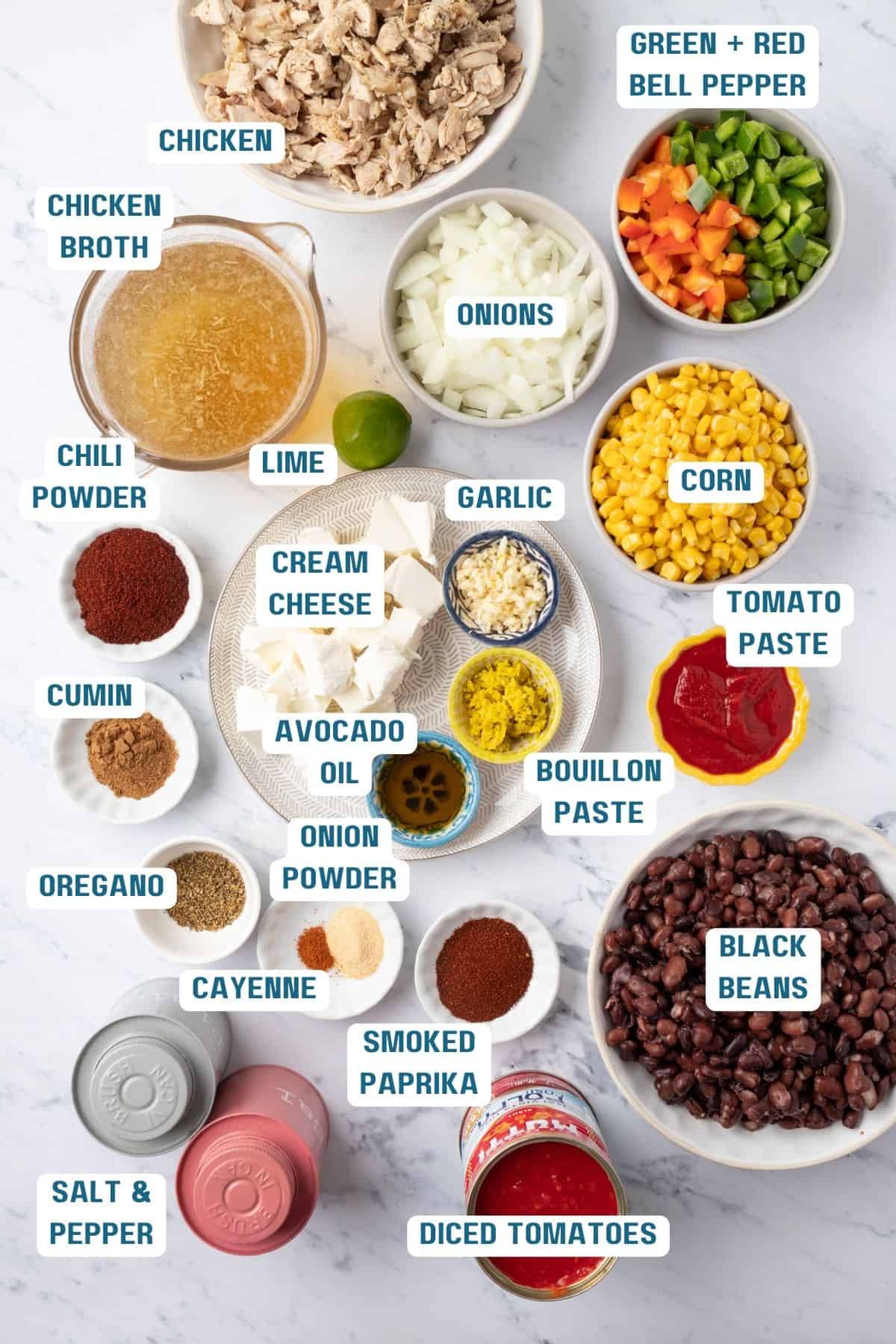 Ingredients to make chicken taco soup on the table with labels to identify each.