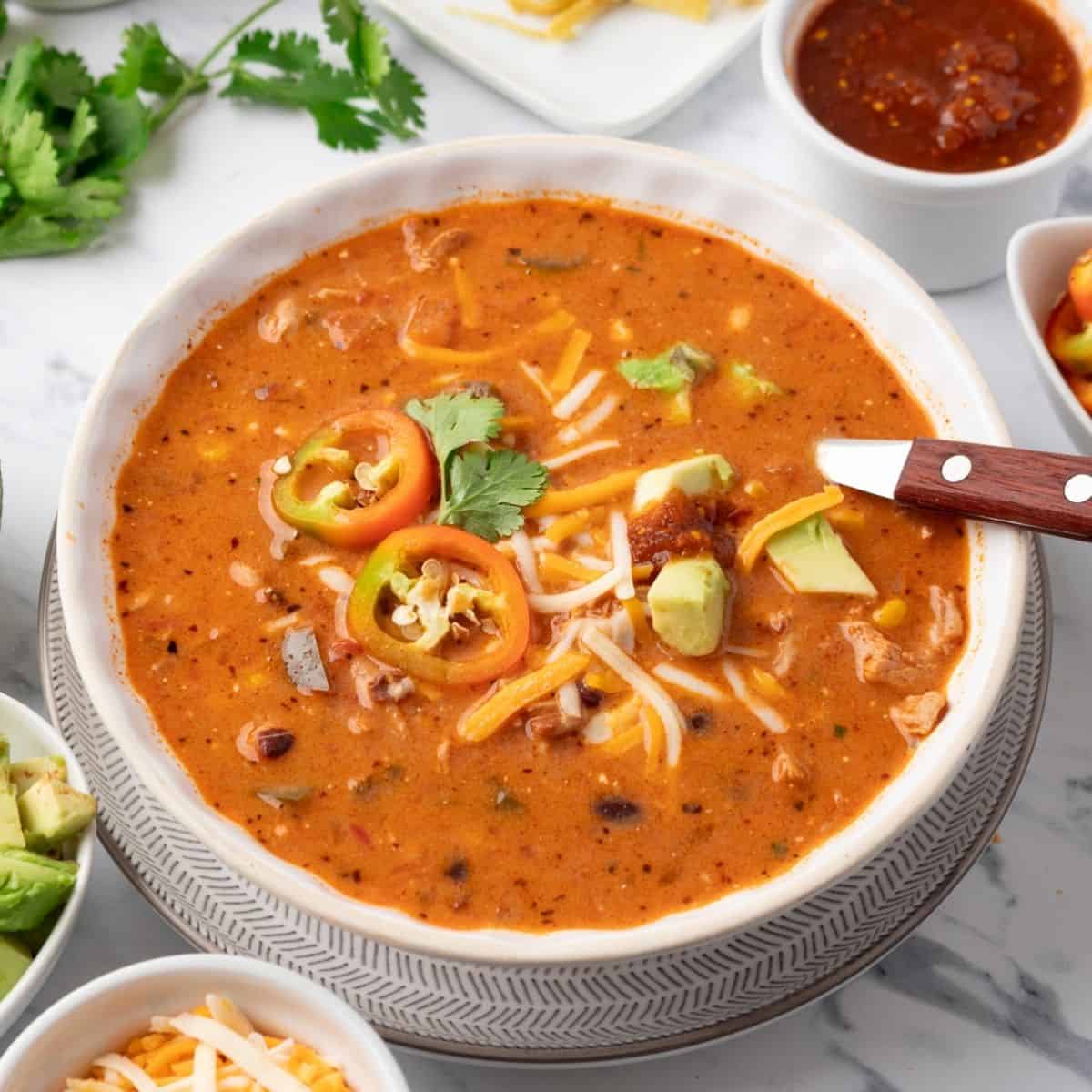 A bowl of creamy chicken taco soup with a spoon resting in the dish.