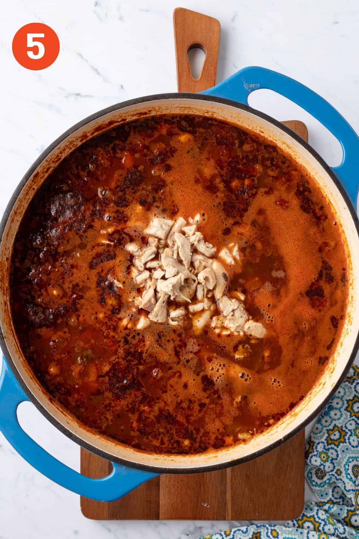 Chicken added to the pot of soup.