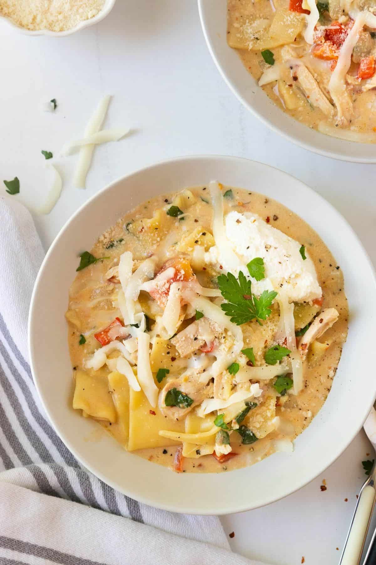 A bowl of white chicken lasagna soup on the table.