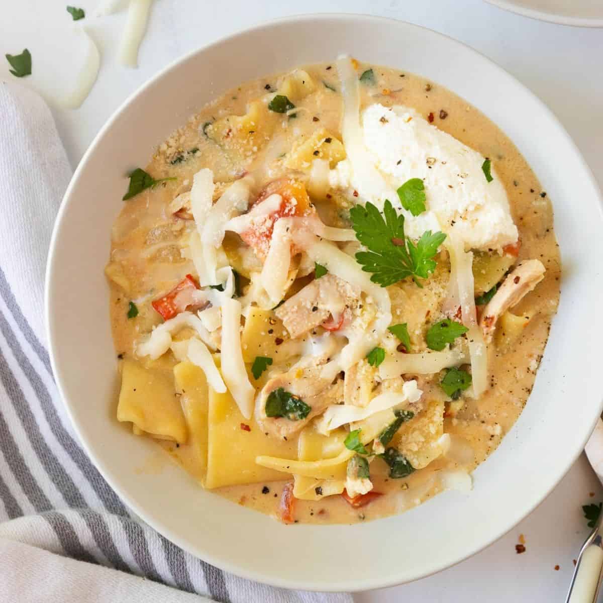 A white bowl of creamy white chicken lasagna soup.