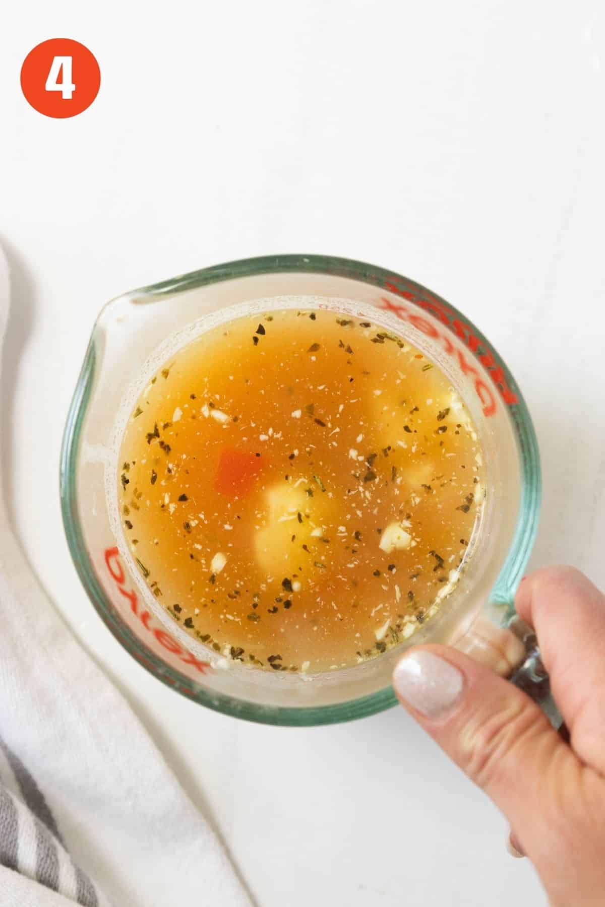 Cream cheese in a measuring cup with some hot broth.