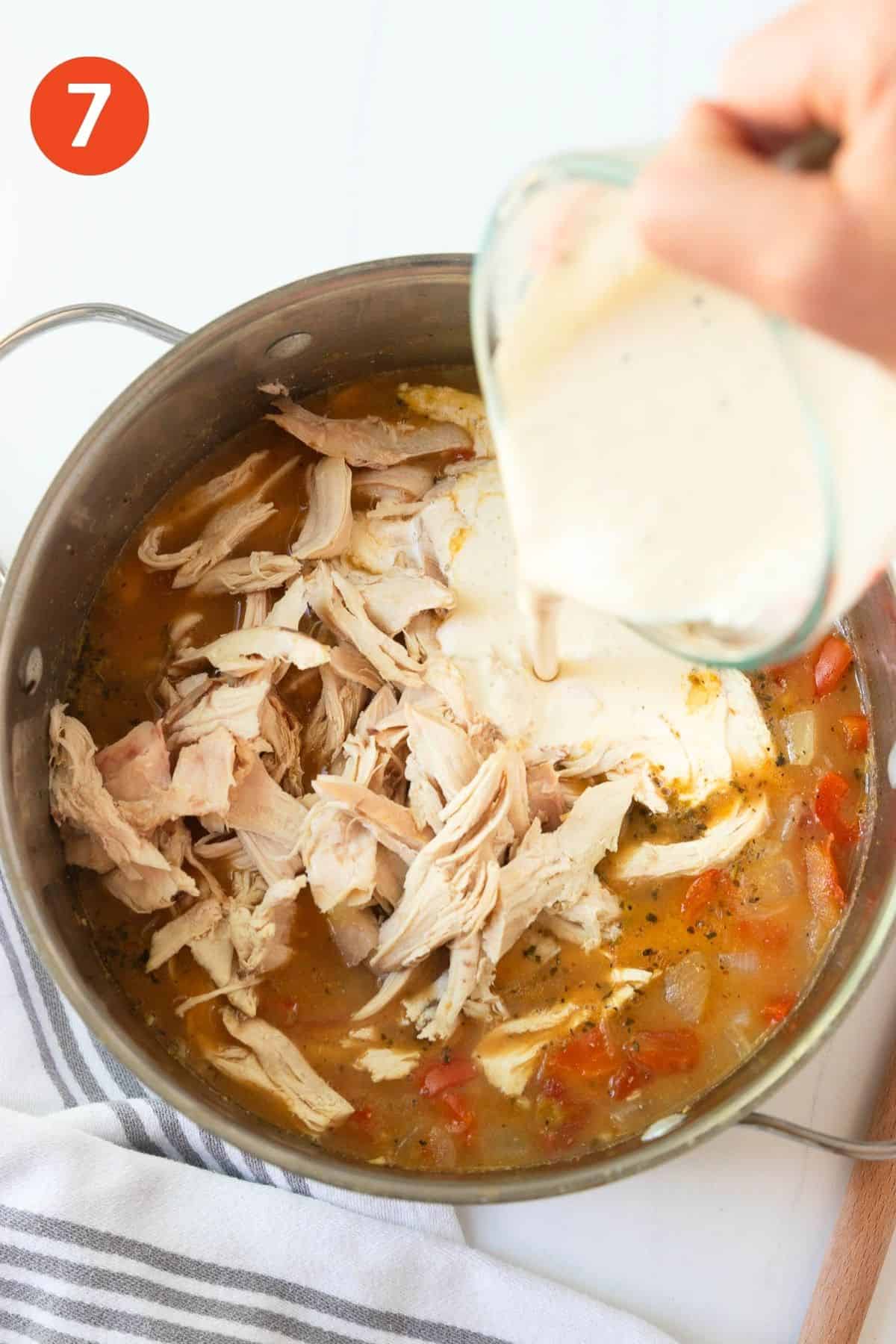 Adding the shredded chicken and cream cheese mixture to the pot of soup.