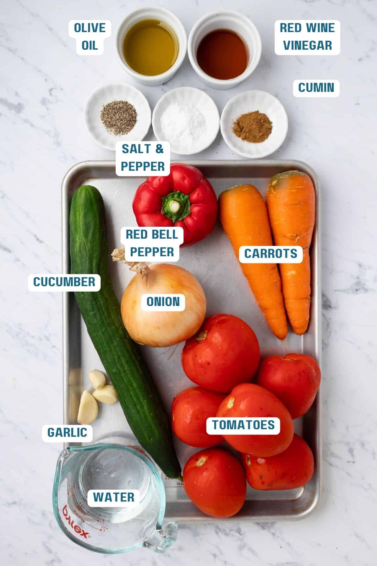 Ingredients to make roasted tomato gazpacho on a baking sheet.