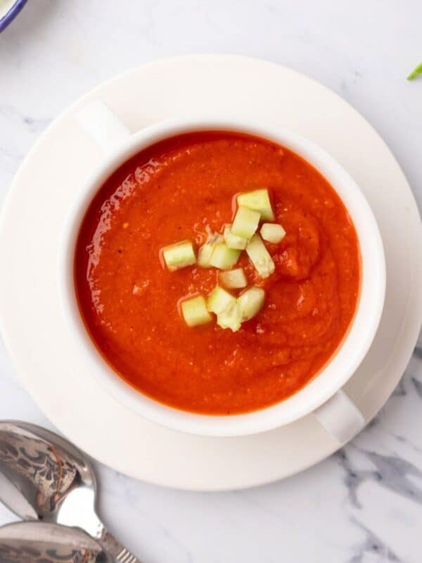 A bowl of cold tomato soup made with roasted tomatoes and garnished with cucumber.