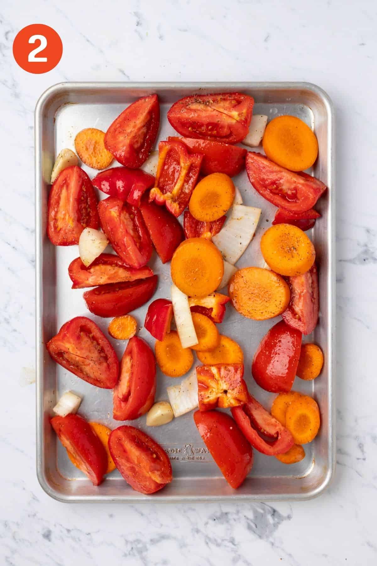 Vegetables spread out on a pan to roast.