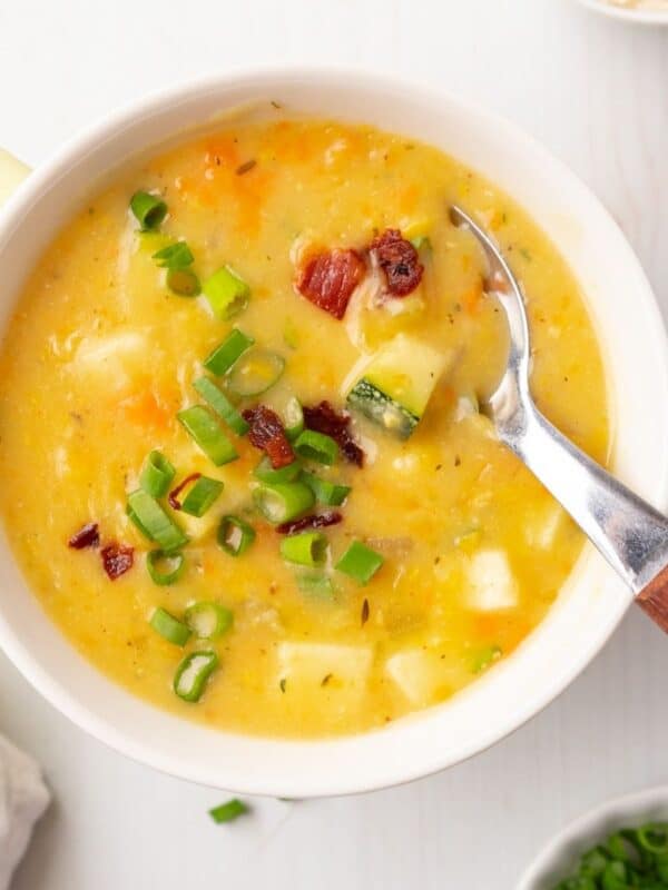 A bowl of zucchini corn chowder with a spoon resting in the bowl.