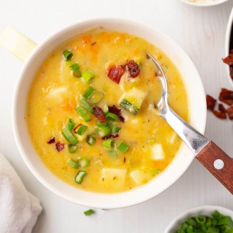A bowl of zucchini corn chowder with a spoon resting in the bowl.