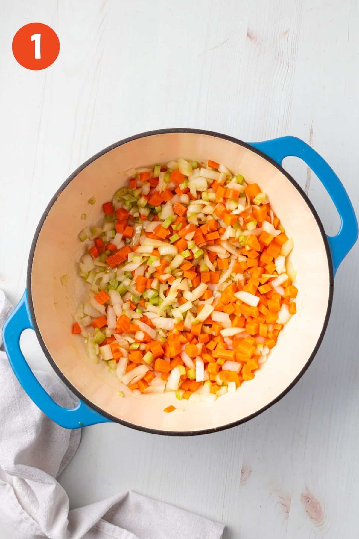 Carrots, celery, and onion cooking in a pot.