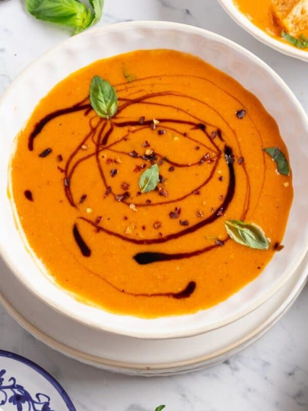 Roasted tomato basil soup with balsamic syrup drizzled and fresh basil on top.