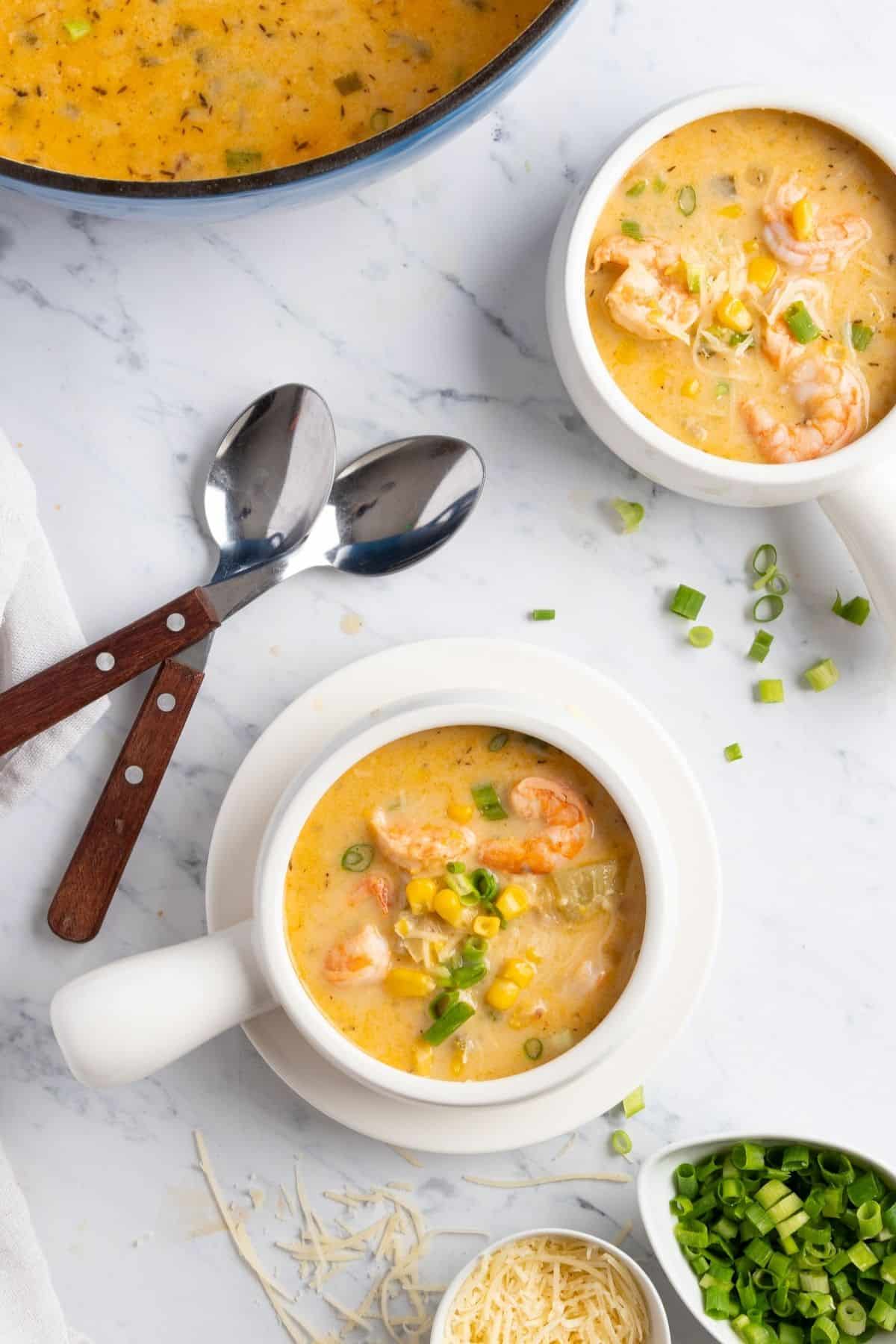 Bowls of shrimp and corn chowder along with the pot on a table.