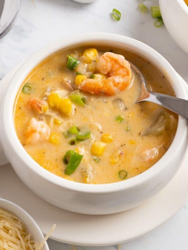 A bowl of shrimp corn chowder with a spoon in the bowl.
