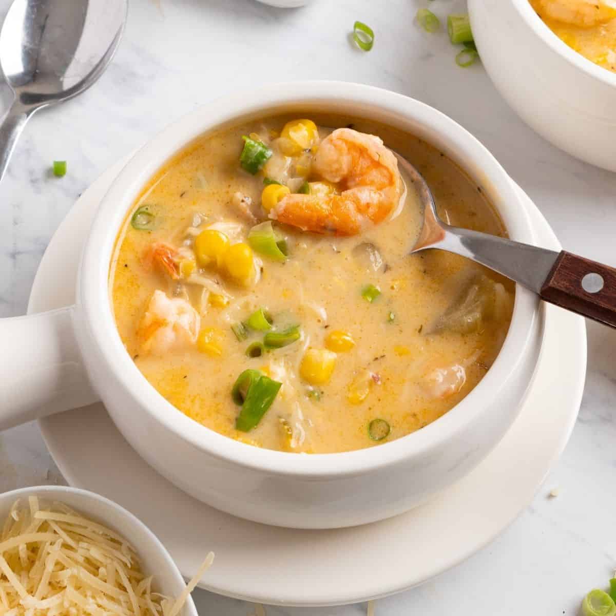 A bowl of shrimp corn chowder with a spoon in the bowl.