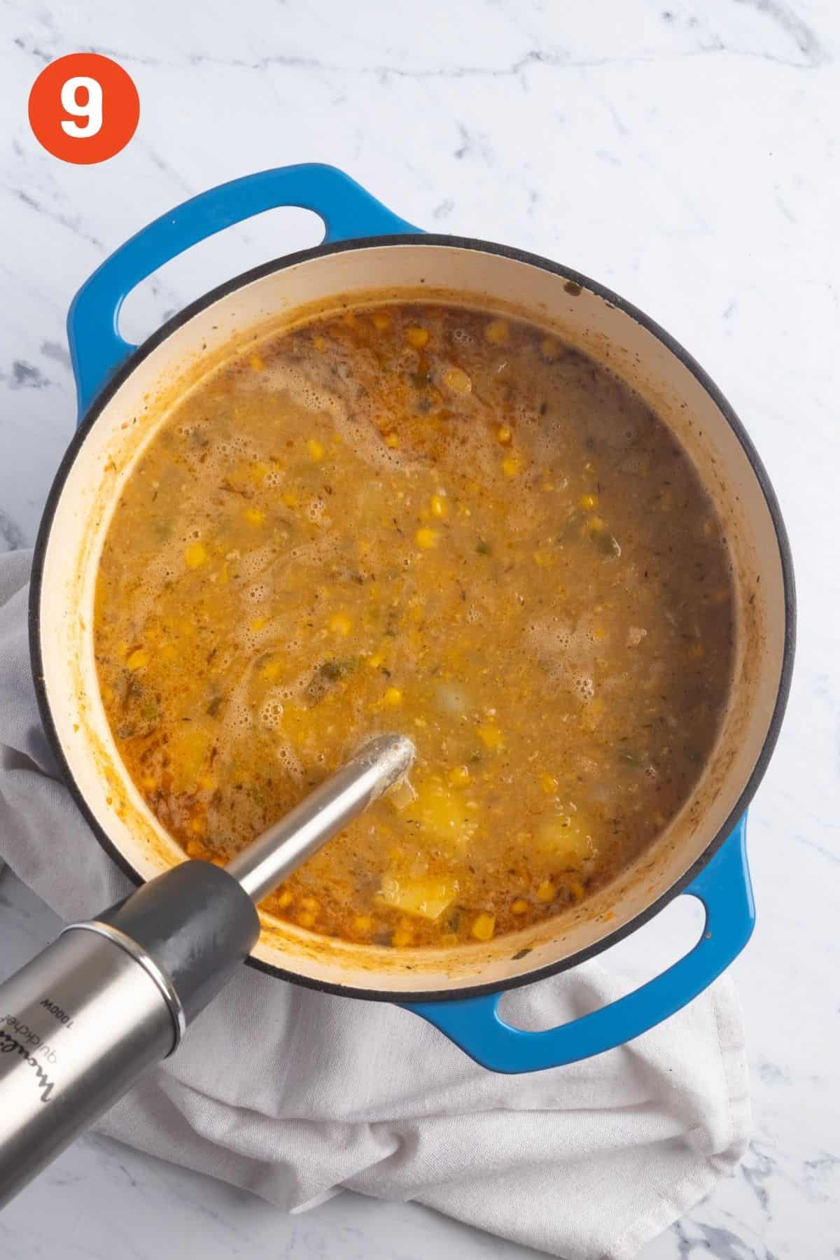 An immersion blender in the pot of soup.