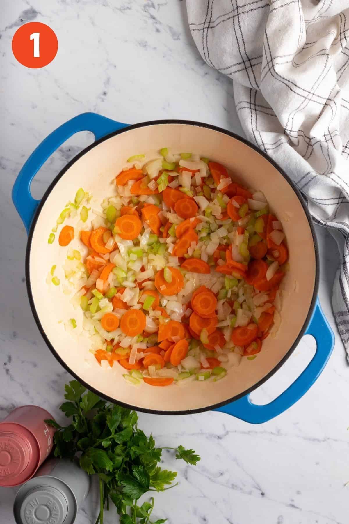 Onion, celery, and carrots cooking in butter in a Dutch oven.